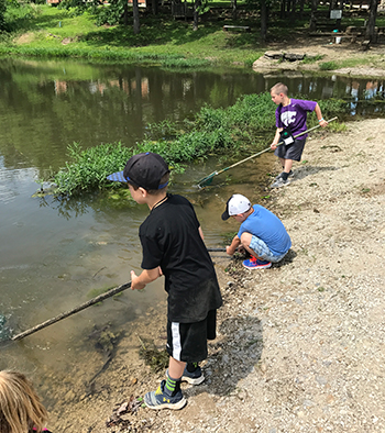 4-H youth at camp cleaning pond