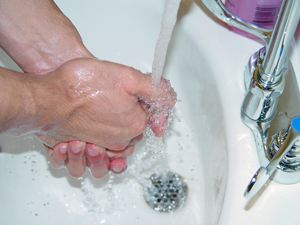 Washing hands under a sink.