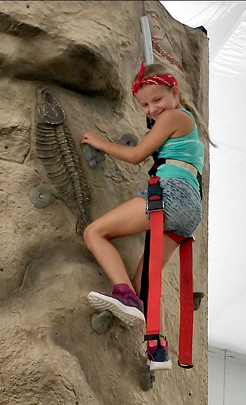4-H youth climbs rock wall at summer camp
