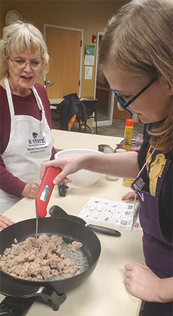 volunteer helping a girl cook