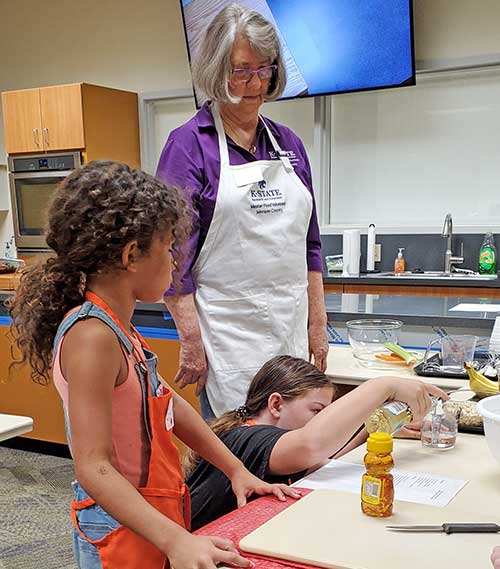 woman helping kids cook