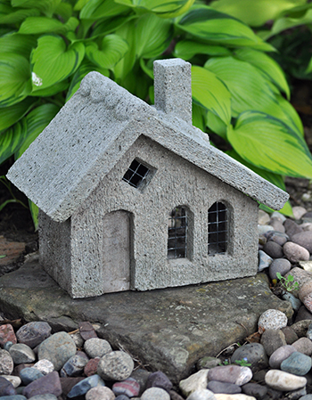 Concrete faerie house in front of hosta