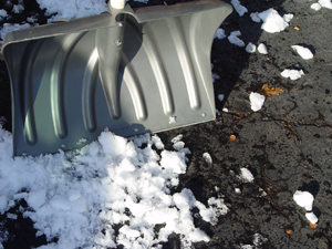 Snow shovel and snow on driveway