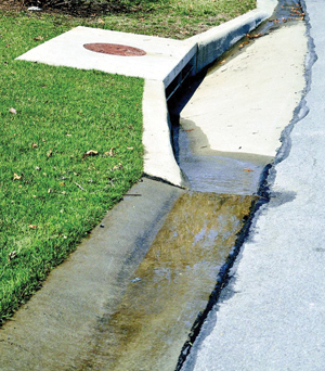 Water running in street gutter into storm drain